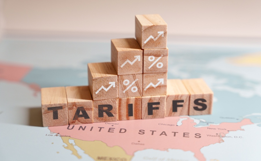 Wooden blocks spelling TARIFFS are placed on a map of North America specifically over the United States and Mexico
